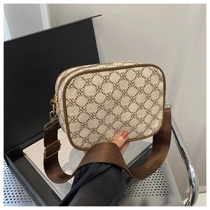 Détail du sac bandoulière beige avec motif trèfle marron et sangle tissée large