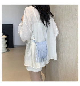 Close-up of light blue tassel crossbody bag showing elegant fringe and leather texture