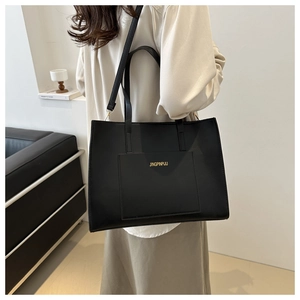 Detail of black faux leather tote bag with gold logo lettering and double handles