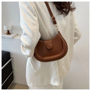 Brown semi-circle saddle bag shown on person to highlight its size and stylish fit