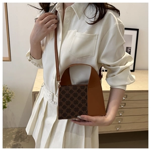 Nahaufnahme einer braunen Patchwork-Handtasche mit Monogramm-Klappe getragen von einem Model