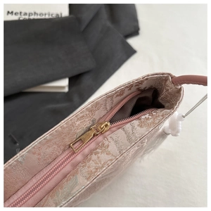 Détail de la fermeture éclair dorée et du tissu en brocart rose du sac chinois chic