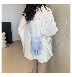 Close-up of light blue tassel crossbody phone bag with fringe detailing and slim strap