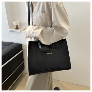 Close-up of black leather tote bag with gold lettering and adjustable shoulder strap