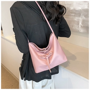 Pink shoulder bag detail showing soft textured fabric and ribbon drawstring bow design