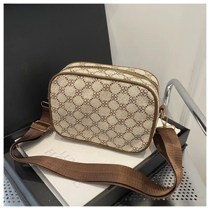 Détail du sac bandoulière beige à motifs floraux avec sangle large et boucles dorées