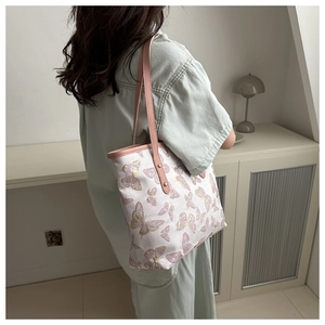 Close-up of butterfly print tote bag with pink leather strap and gold rivet details