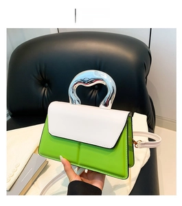 Détail du sac à main bicolore vert et blanc avec poignée métallique argentée incurvée