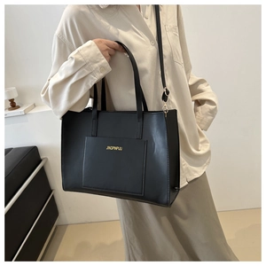 Detail of minimalist black tote bag featuring gold lettering and adjustable shoulder strap