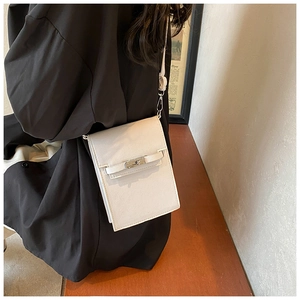Detailed view of a white rectangular leather cross-body bag with metallic buckle and slim strap