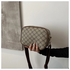 Gros plan du sac bandoulière kaki avec motif trèfle et bandoulière réglable