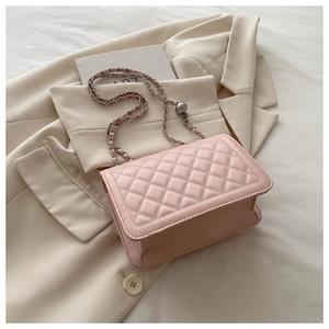 Detail of pink quilted leather bag with chain strap and gold bead on cream blazer