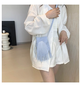 Detail shot of light blue tassel crossbody bag with matte leather and slim shoulder strap