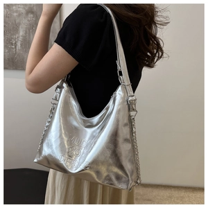 Detail of silver metallic tote bag featuring embossed logo and decorative chain strap