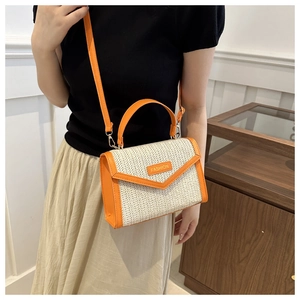 Detail of a straw woven crossbody bag with orange leather trim and gold hardware