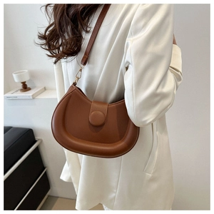 Close-up of brown crescent shoulder bag with puffy edges and gold metallic buckle