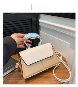 Détail du sac à main bicolore avec une poignée métallique argentée en forme de cœur