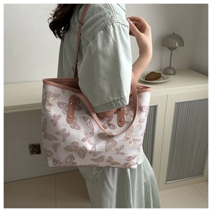 Close-up of pink butterfly embroidery on a white canvas tote with leather straps