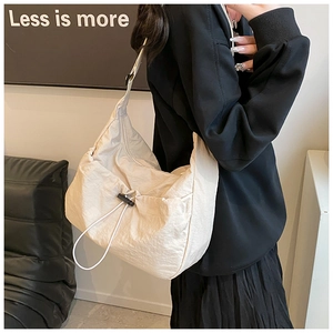 Detail of a large cream nylon hobo bag featuring a drawstring closure and wrinkled texture