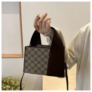 Detail der modischen kleinen quadratischen Handtasche mit Kleemuster und Lederriemen