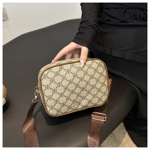Détail d'un sac bandoulière rétro beige et marron avec motif trèfle et boucles dorées