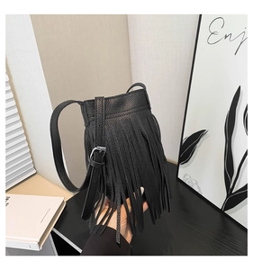 Macro detail of black leather bucket bag featuring long fringe tassels and silver hardware