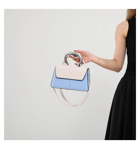 Détail d'un sac à main bicolore avec poignée sculpturale en métal argenté et cuir bleu clair