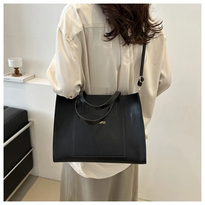 Model view of black leather tote bag with square pocket and golden logo for daily commute