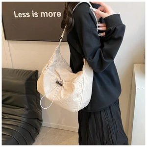 Detail of minimalist beige pleated tote bag showing fabric texture and drawstring feature