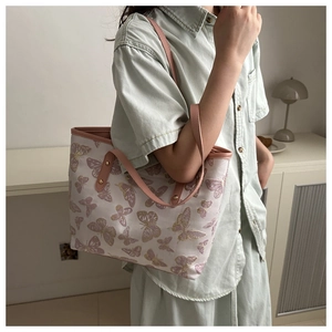 Close-up of pink butterfly embroidery and premium leather straps on a large tote bag