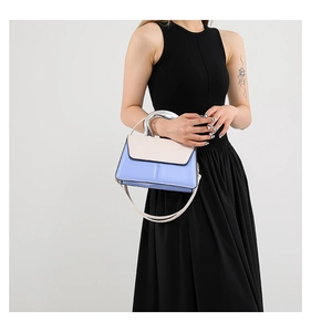 Détail du sac bicolore bleu et crème avec une grande poignée en métal argenté en forme de U