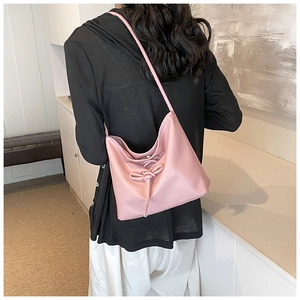 Detail of pink hobo shoulder bag featuring a decorative drawstring bow and sleek texture