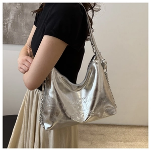 Modèle portant un sac cabas argenté effet miroir avec bandoulière chaîne et lettrage