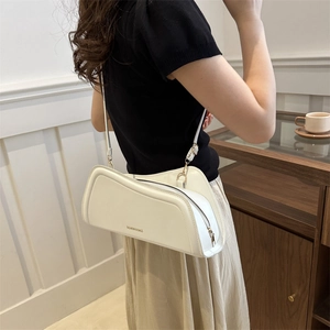 Minimalist white leather underarm bag with unique curved geometry and slim shoulder strap