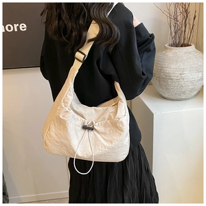 Detail of beige nylon crossbody bag with pleated texture and adjustable black strap