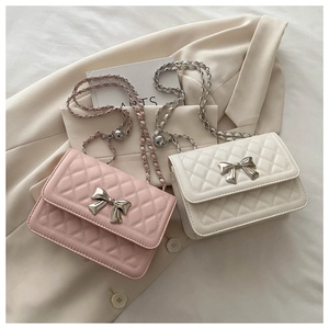 Detail of quilted chain bags in pink and beige with decorative metal bow buckles