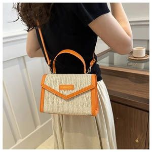 Détail d'un sac bandoulière en paille avec bordure orange et plaque logo FASHION