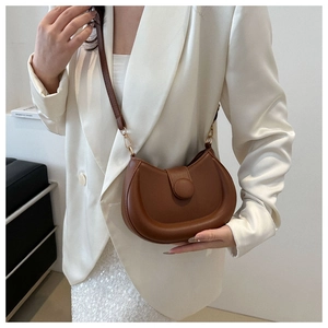 Detail view of deep brown semi-circle saddle bag with decorative buckle and gold hardware
