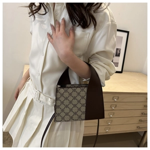 Schicke beige Handtasche mit dunkelbraunem Kleeblattmuster in Lifestyle-Einstellung