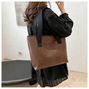 Detail of dark brown geometric patchwork tote bag shown on a model's shoulder