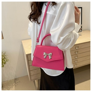 Detail of rose pink leather square bag featuring a 3D silver metal bow ornament