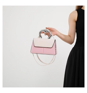 Vue détaillée du sac à main en cuir rose et blanc avec une poignée moderne en métal argenté