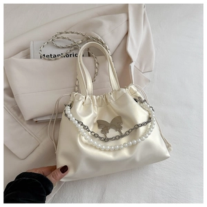 Detailed view of cream satin bucket bag with silver butterfly buckle and pearl chain