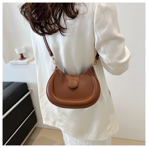 Detailed back view of vintage brown crescent leather bag worn over a white suit blazer