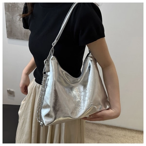 Detail of silver metallic tote bag featuring embossed logo and decorative chain strap