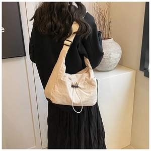 Detail of off-white crossbody tote with drawstring ruched design and black adjustable buckle