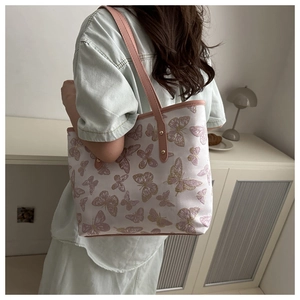 Detail of floral butterfly embroidery on white tote bag with pink leather shoulder strap