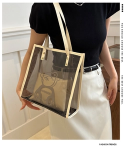 Detail of transparent PVC tote bag with bear motif inner pouch and gold rivet handles