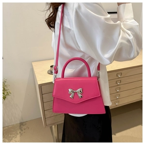 Detail showing rose pink faux leather bag with silver metal bow and crossbody strap