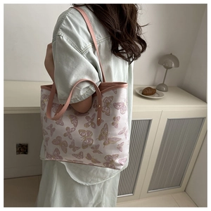Detail view of large butterfly print tote bag with pink leather handles in a lifestyle setting